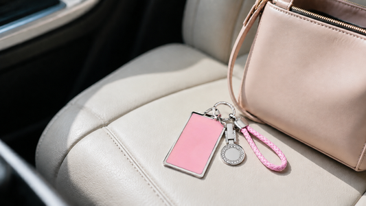Pink Tesla key card holder with braided wrist loop beside a handbag on a car seat