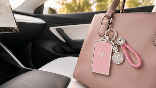 Pink crystal key card holder with braided wristlet attached to a blush handbag inside a modern electric car