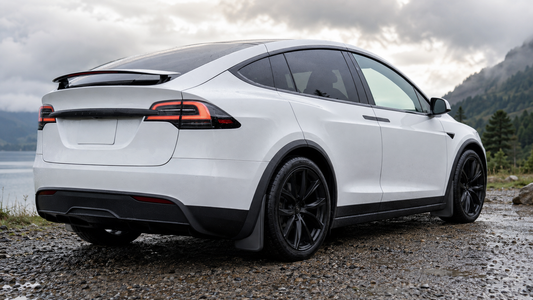 Black no-drill mud flaps installed behind the wheels of a white 2022–2026 Model X